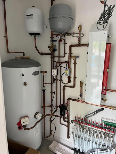 Hot-water cylinder, expansion vessels, copper pipework and heating manifold arranged within a utility cupboard