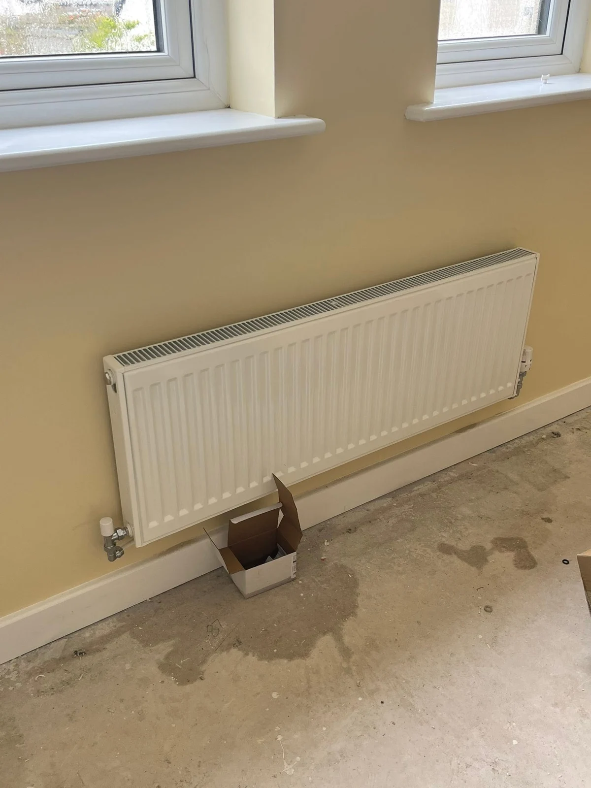 White panel radiator fitted beneath windows during a property renovation